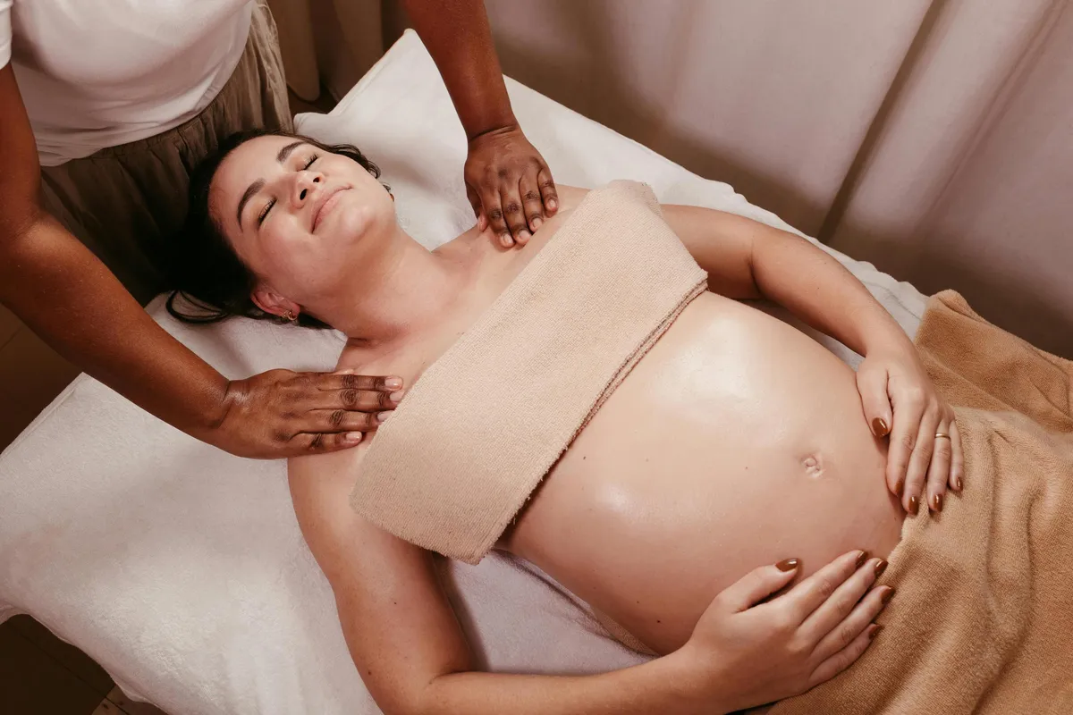 Une personne allongée reçoit un massage sur le ventre par deux mains, entourée de serviettes