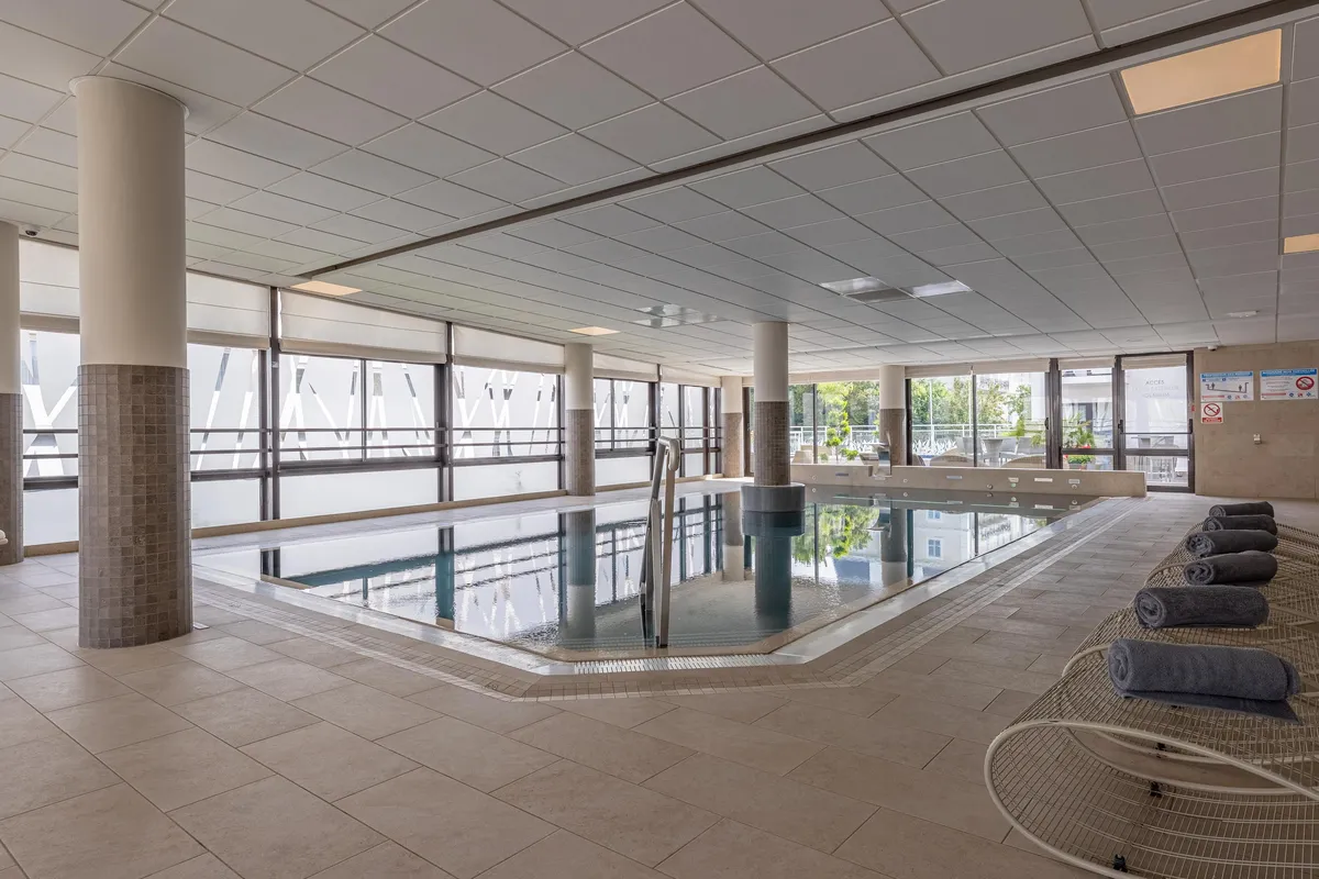 Innenpool mit Säulen, Fenstern und Handtüchern auf Liegestühlen