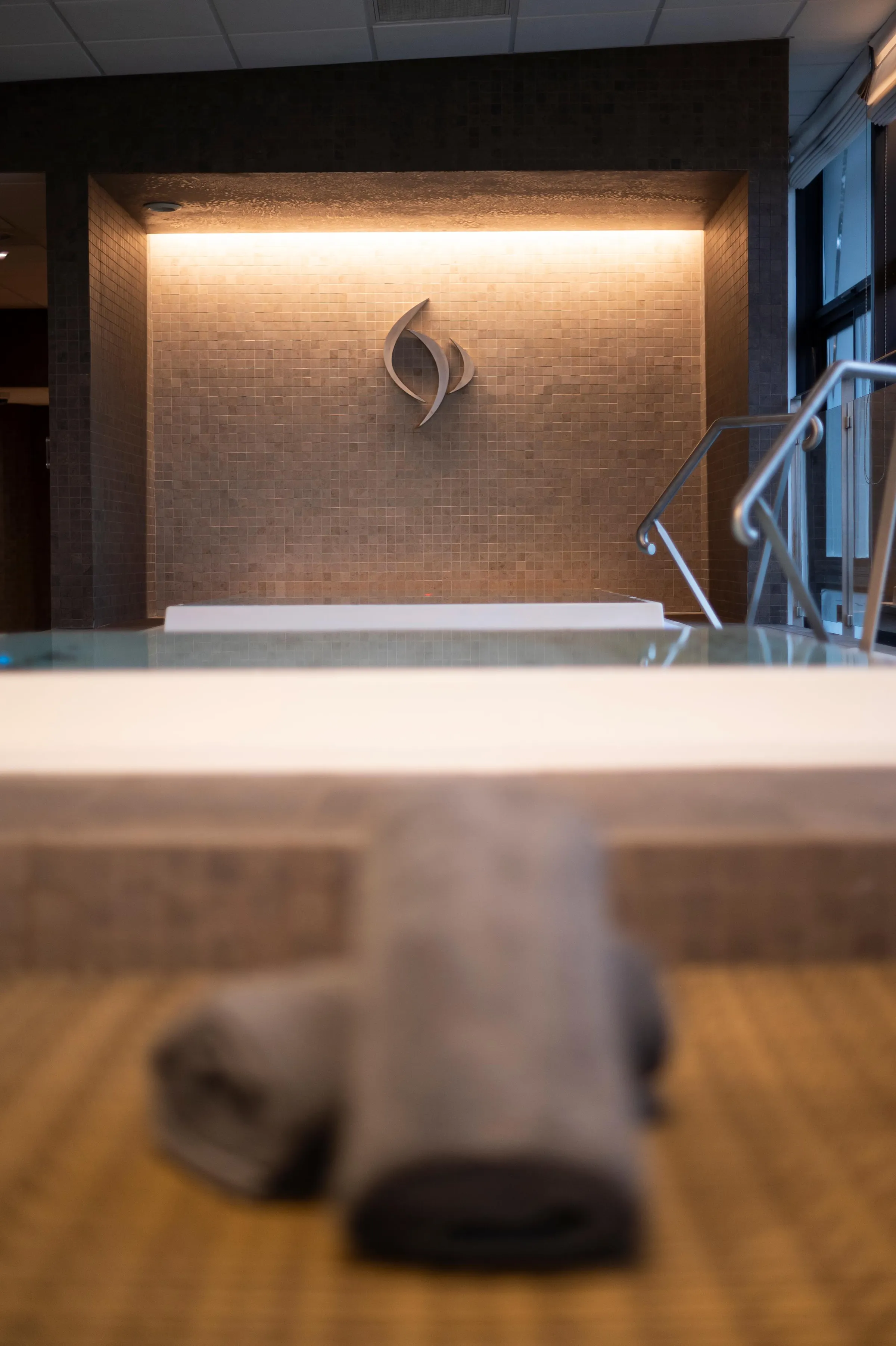 A water basin with a tiled back wall and a metal wall sculpture